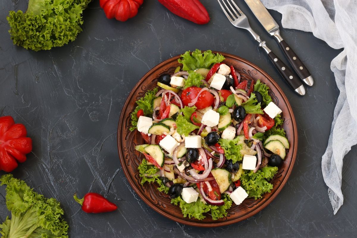 Healthy salad of lettuce, tomato, red onion, pepper, soft cheese, olives, basil, cucumbers,  with olive oil and lemon juice. Greek salad Copy space